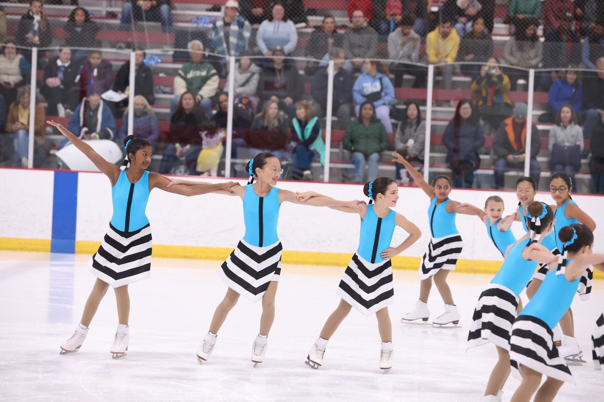 The aspire 3 team from richmond va in a closeup smiling while skating a routine in a competition in blue costumes.