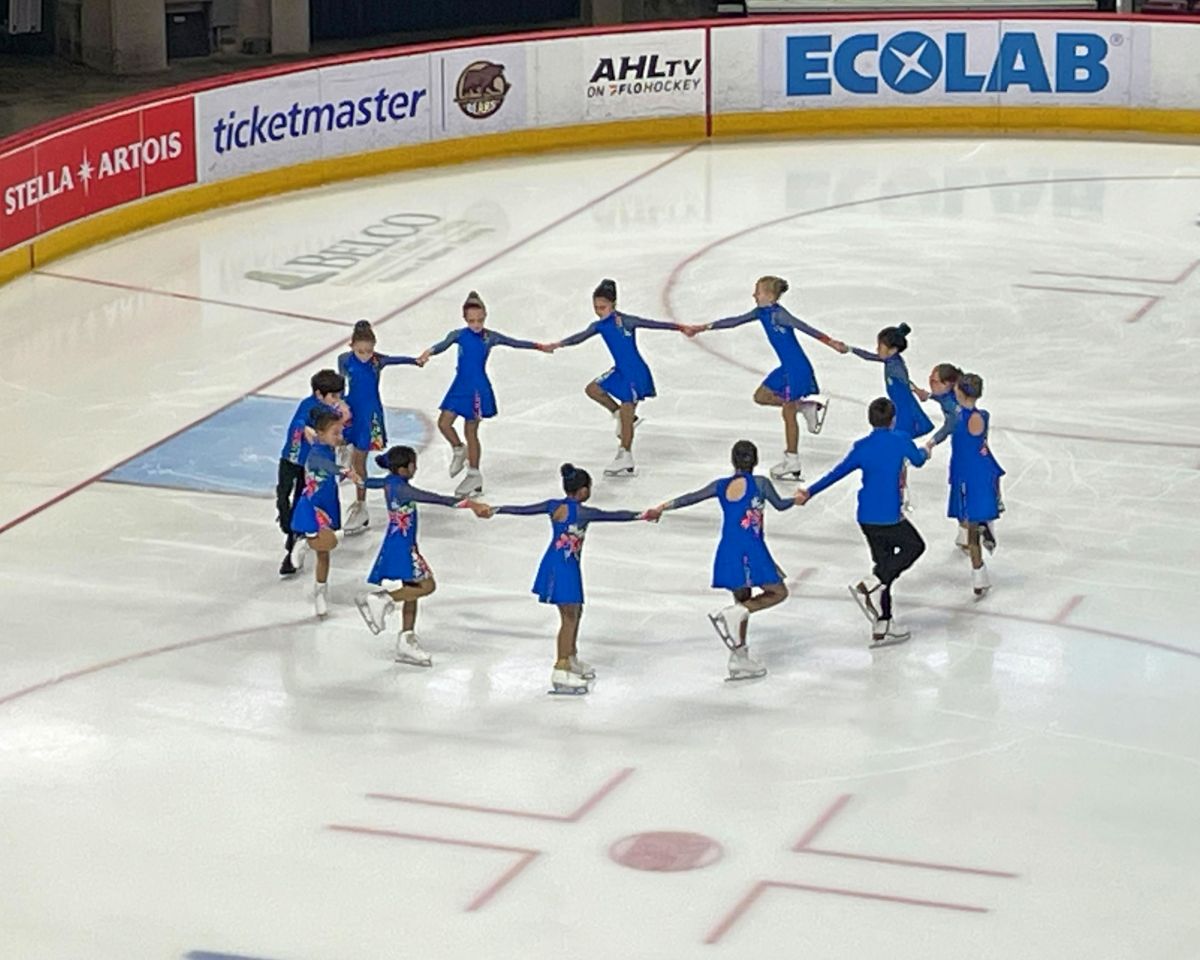 aspire 1 synchronized figure skating team from richmond va performing on ice in blue costumes.