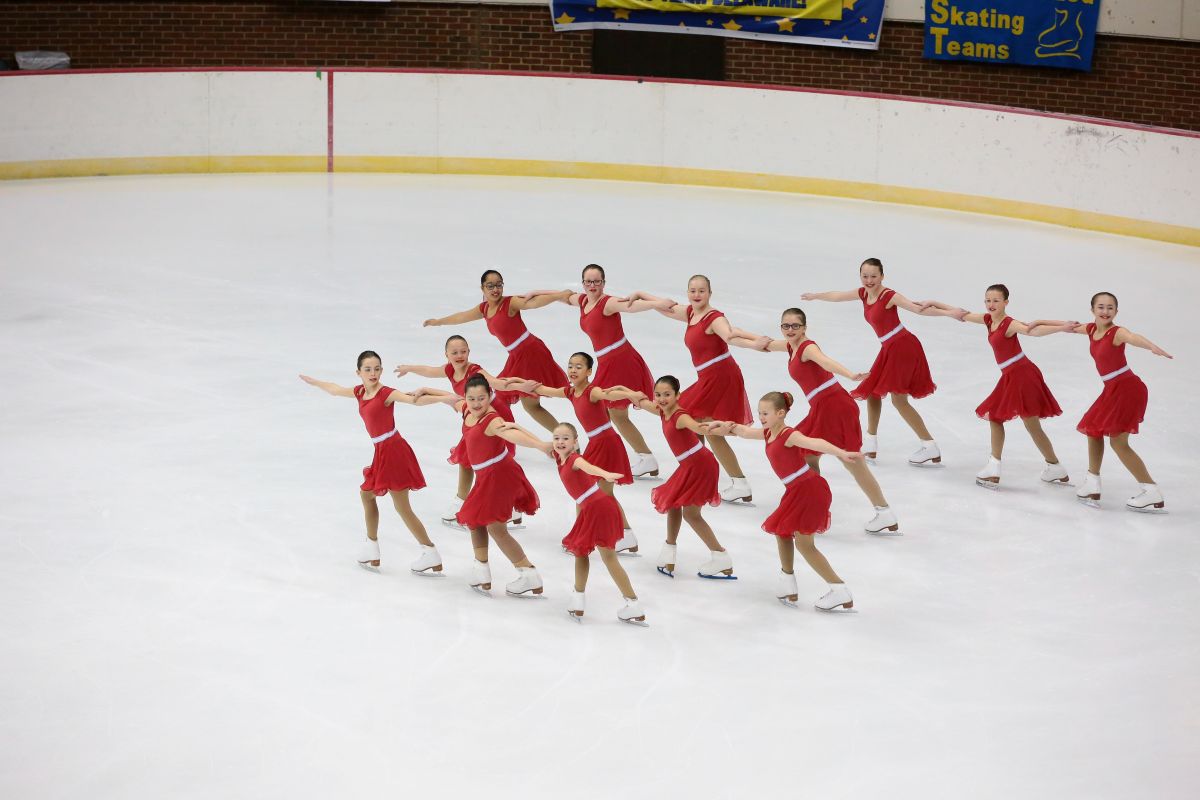 Aspire 3 team in red costumes performing on ice skating as a group in a competition