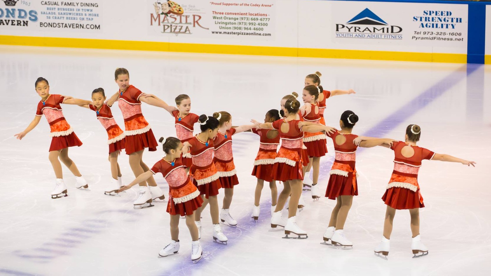richmond skating synchro aspire 1 team performing on ice at a competition in red costumes